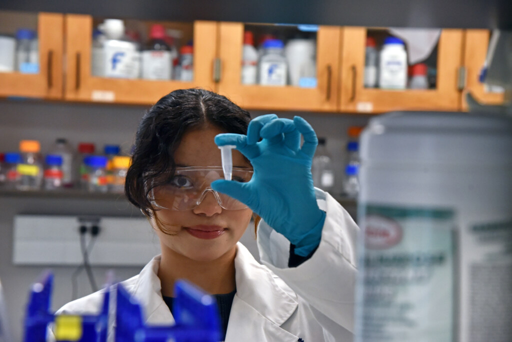 A man with a mask on working in a lab on quantum computer hardware.